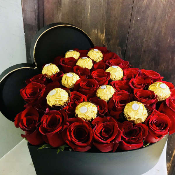 Heart-shaped box filled with red roses and gold-wrapped chocolates