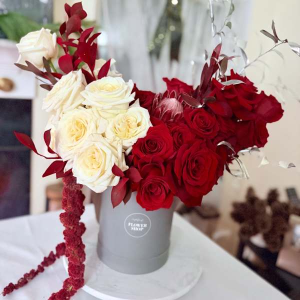 Red and white roses arranged in a gray hat box