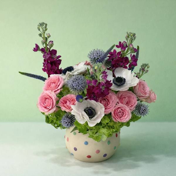 Pink and white floral arrangement in a polka-dot ceramic pot