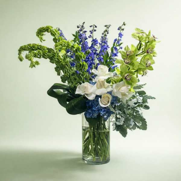 Blue, white, and green floral arrangement in a clear glass vase