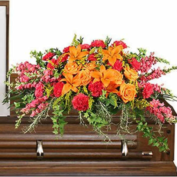 Bright floral spray arranged on top of a wooden casket