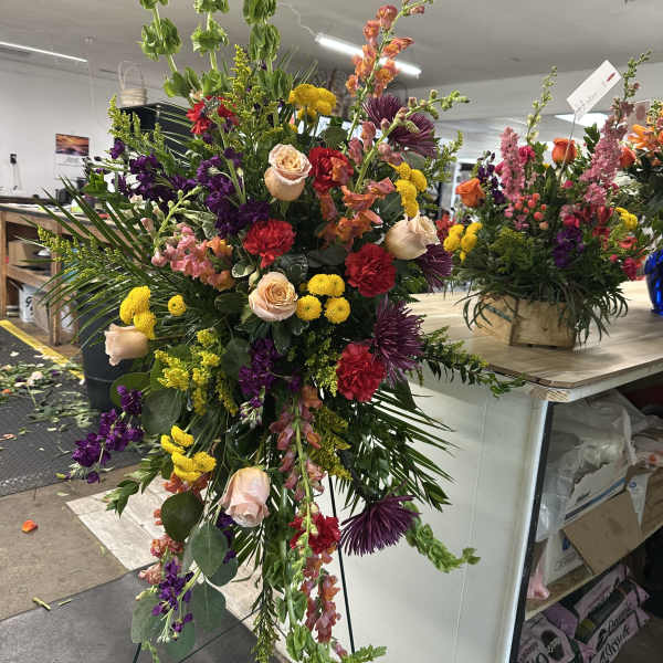 Tall standing floral spray with roses, carnations, and purple blooms