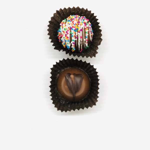 Two decorated chocolate truffles in brown paper cups on a white background