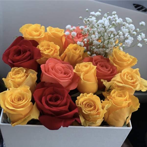 Red, yellow,pink roses and baby breath arrangement in a white box by lav.ishbouquets
