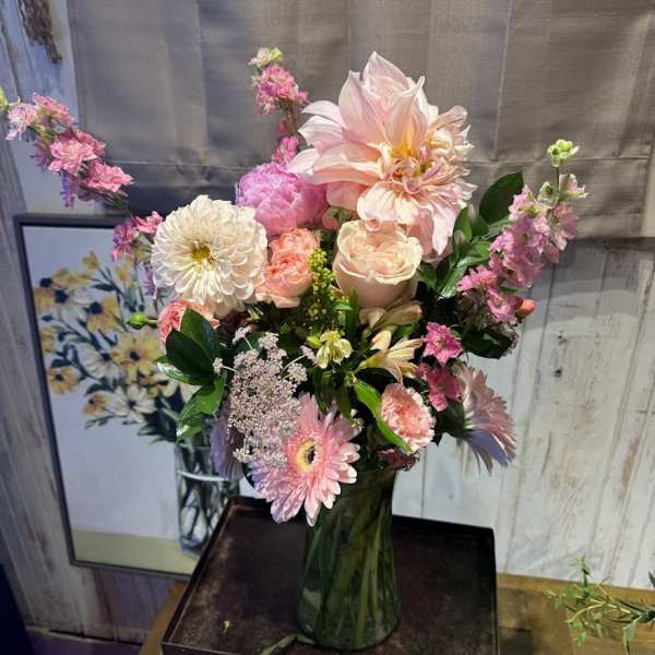 Pastel pink and white mixed flower arrangement with dahlias, roses, and gerberas in a clear glass vase