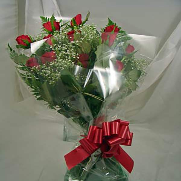 Bouquet of red roses and white filler flowers wrapped in clear cellophane with a red bow