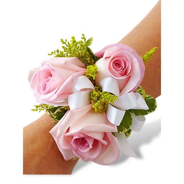 Pink rose wrist corsage with white ribbon on a person’s arm