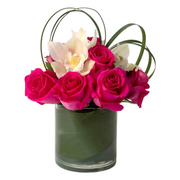 Short arrangement of hot pink roses and white orchids in a leaf-lined glass cylinder vase