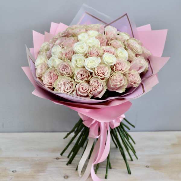 Large hand-tied bouquet of pale pink and ivory roses wrapped in layered pink paper and ribbon.