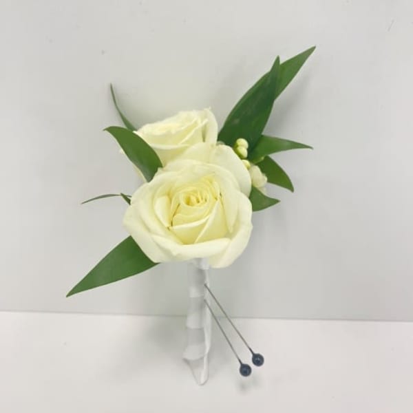 White rose boutonniere with greenery and wrapped stem on a white background
