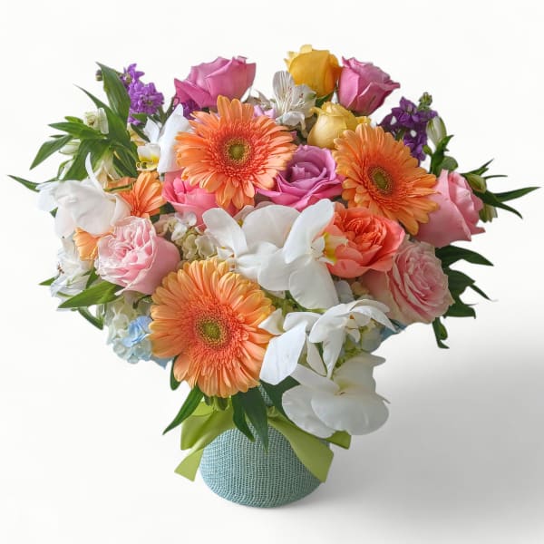 Colorful bouquet of peach gerbera daisies, roses, and white orchids in a round vase