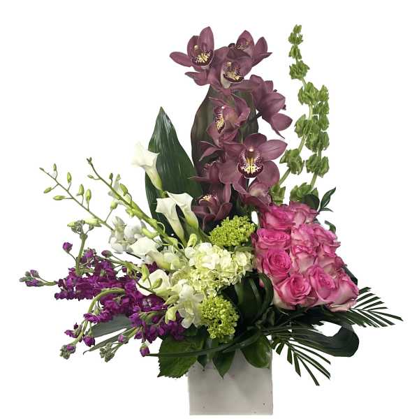 Tall modern arrangement with mauve orchids, pink roses, and white blooms in a white cube vase.