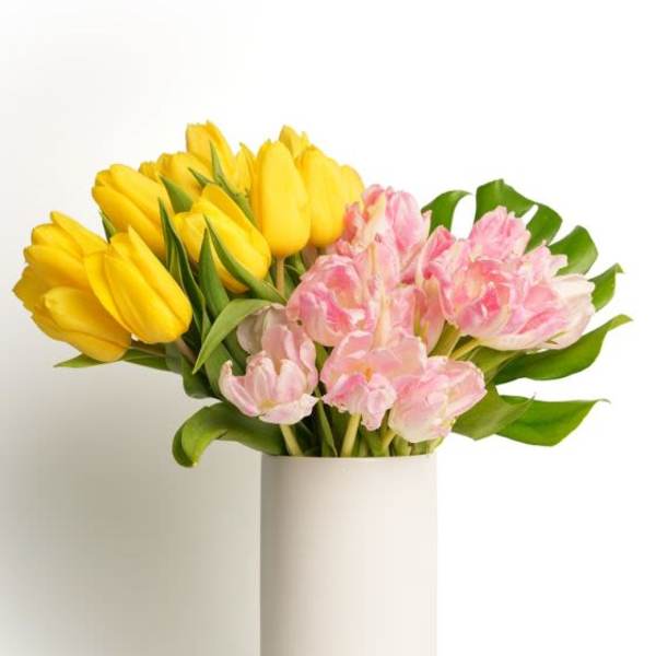 Tall white vase with yellow and pink tulips arranged in two color blocks