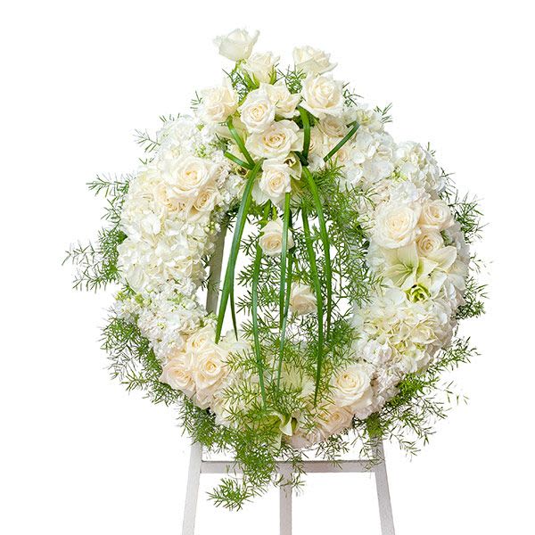 Standing wreath of white roses and hydrangeas with cascading greenery on an easel