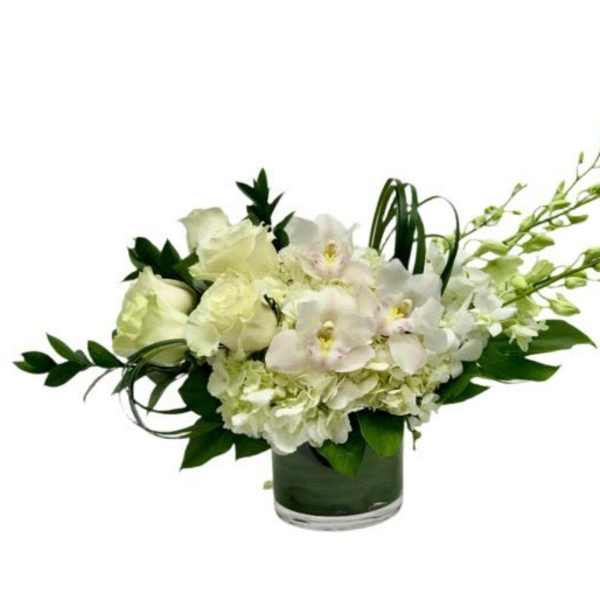 Low white rose and orchid arrangement with hydrangea in a clear glass cylinder vase