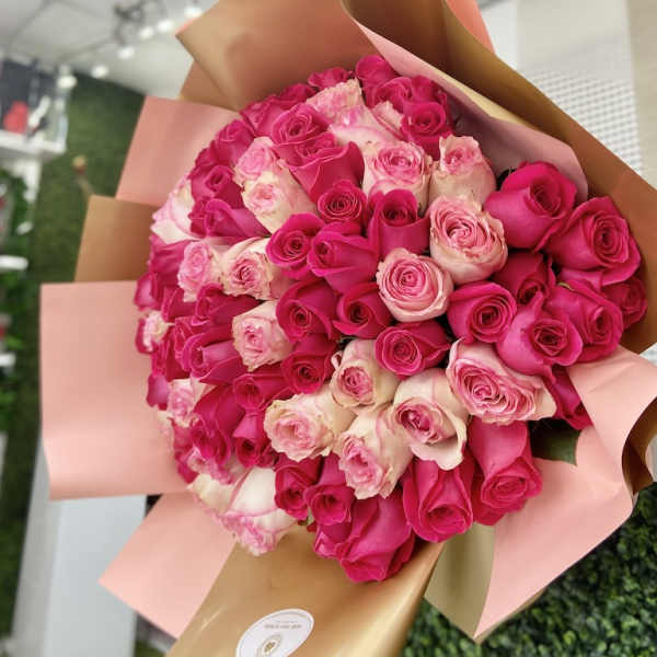 Large hand-tied bouquet of hot pink and light pink roses wrapped in blush and gold paper