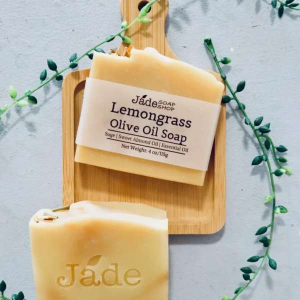 Two beige lemongrass olive oil soap bars on a wooden board with a trailing vine accent.