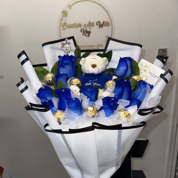 Beautiful arrangement with blue roses, teddy bear in the center, Ferrero Rocher chocolates encapsulated in acrylic
