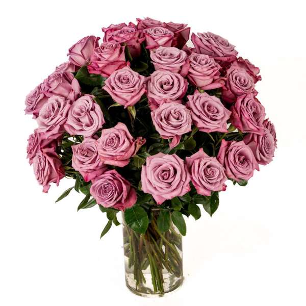 Large bouquet of lavender roses arranged in a clear glass cylinder vase