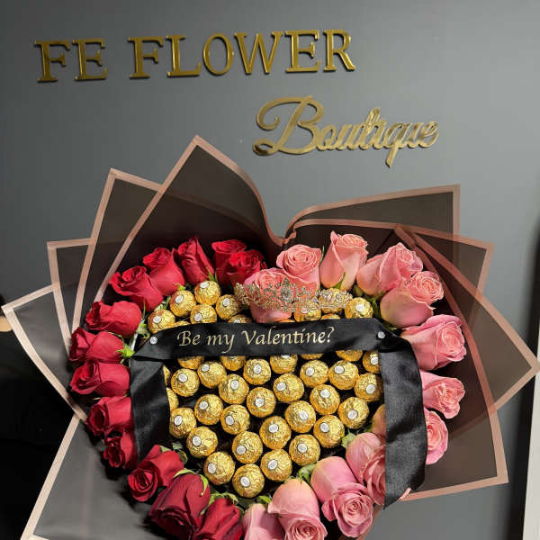 Heart-shaped bouquet of gold-wrapped chocolates framed by red and pink roses with a Valentine ribbon