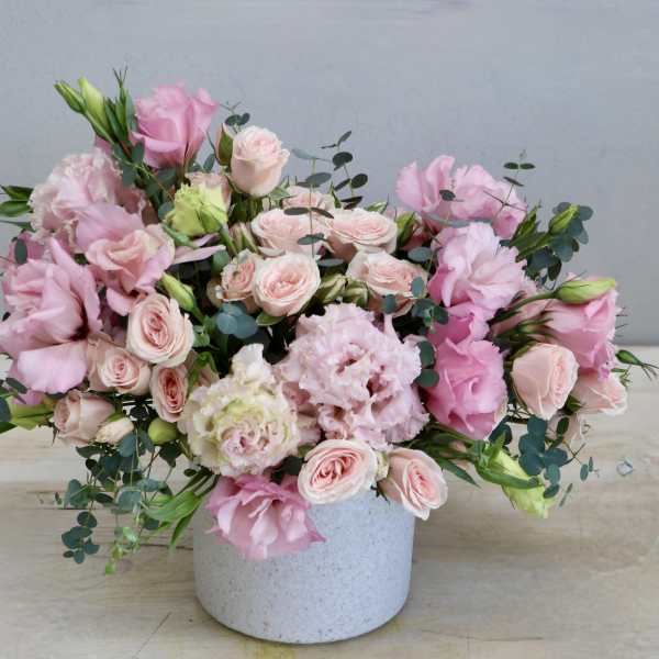 Low pink and blush flower arrangement in a white ceramic pot