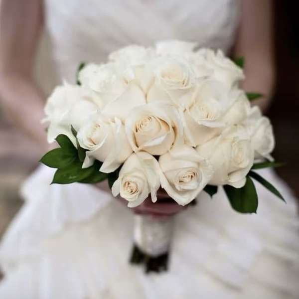 Bride holding a round bouquet of ivory roses.