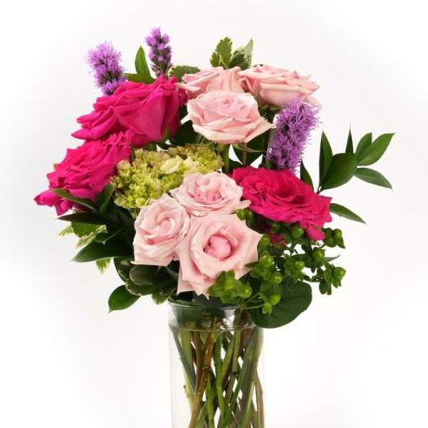 Arrangement of hot pink and light pink roses with green blooms in a clear glass cylinder vase
