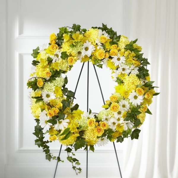 Standing wreath of yellow and white flowers on a metal easel