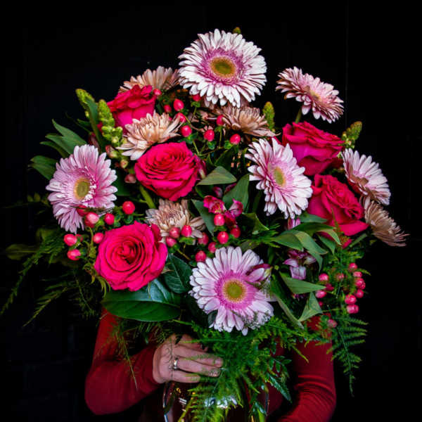 Tall bouquet of hot pink roses and pale pink gerbera daisies in a clear glass vase