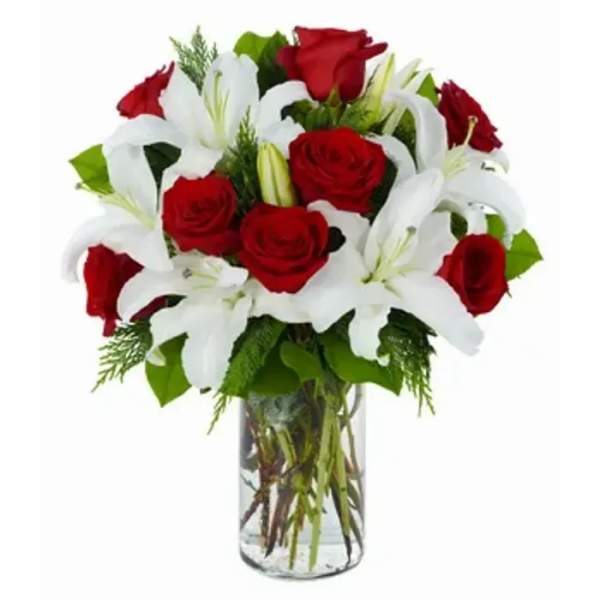 Arrangement of red roses and white lilies in a tall clear glass vase