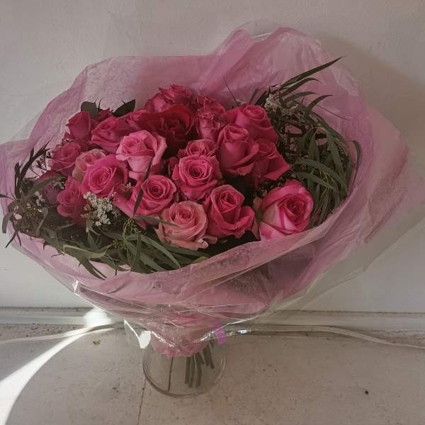 25 hot pink and red roses with greens wrapped or in a vase