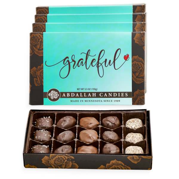 Box of assorted chocolates with teal 'grateful' candy boxes stacked behind it