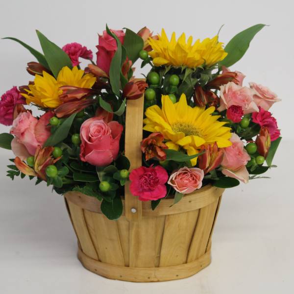 Basket arrangement with yellow sunflowers, pink roses, and bright mixed blooms