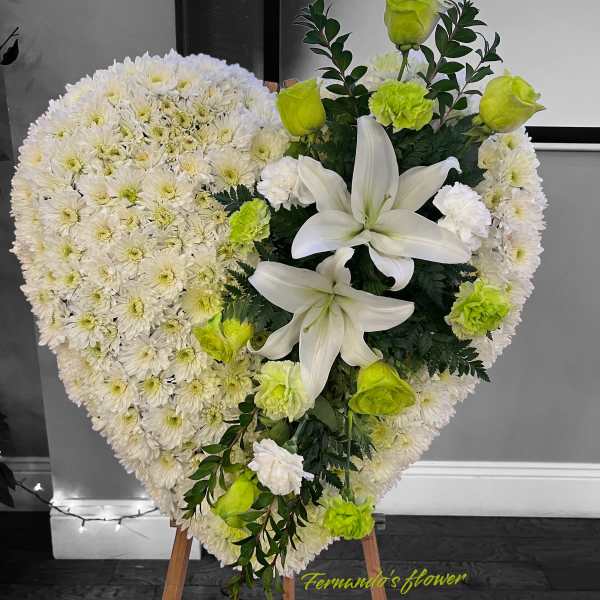 Heart-shaped standing floral arrangement of white flowers with white lilies and green roses.