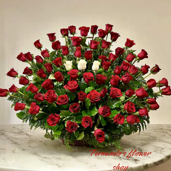 Large fan-shaped arrangement of red roses with a cluster of white roses in a low basket.