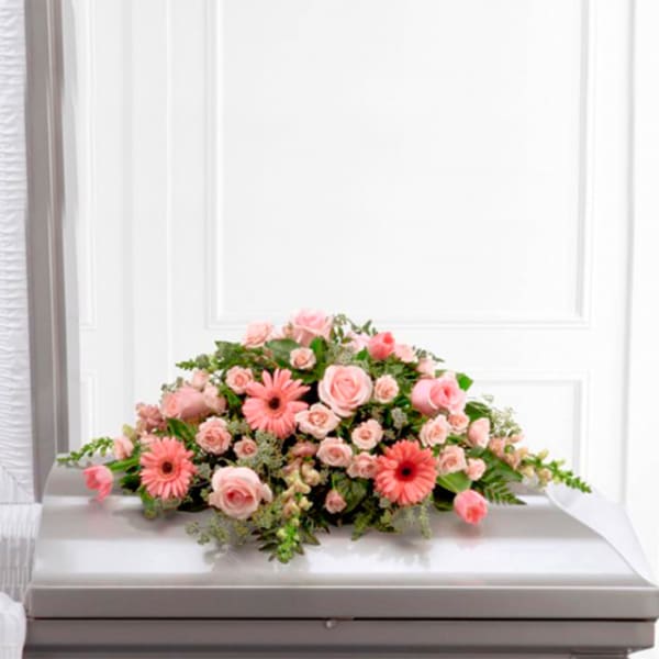 Pink rose and gerbera daisy casket spray on a white casket