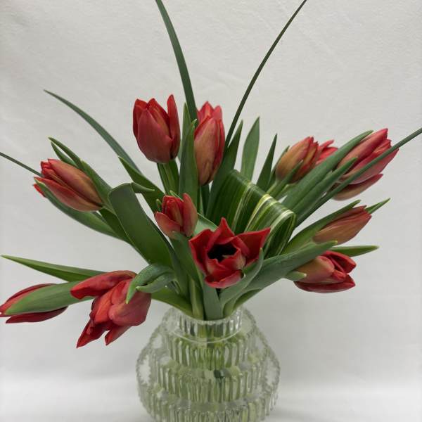 Arrangement of red tulips in a ribbed clear glass vase