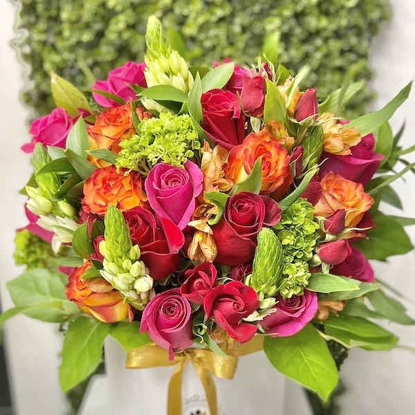 Bright pink and orange mixed bouquet in a white hatbox with gold ribbon