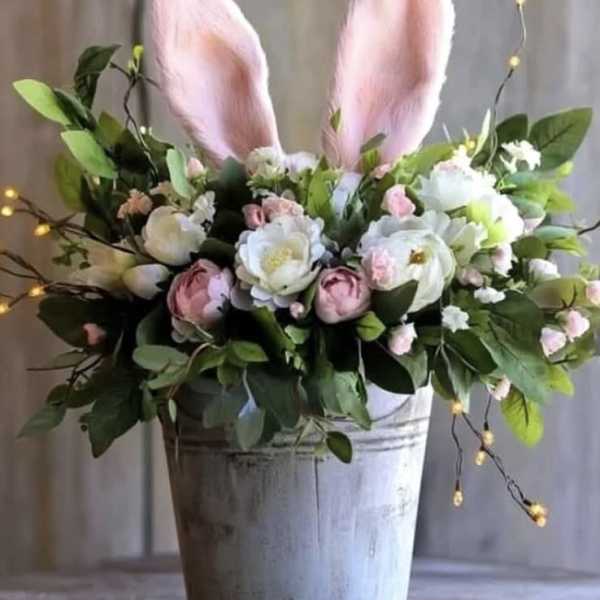 Pastel pink and white flower arrangement with bunny ears in a rustic metal bucket
