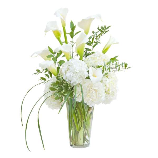 Tall arrangement of white calla lilies and white hydrangeas in a clear glass vase