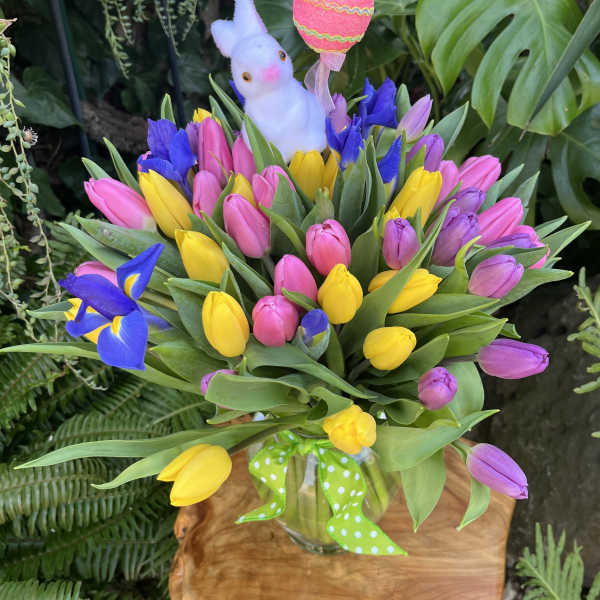 Vase of pink, yellow, and purple tulips with blue irises, bunny pick, and decorative egg