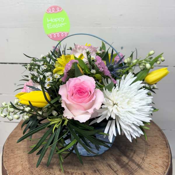 Low Easter flower arrangement with pink rose, yellow tulips, and white mum in a blue bucket