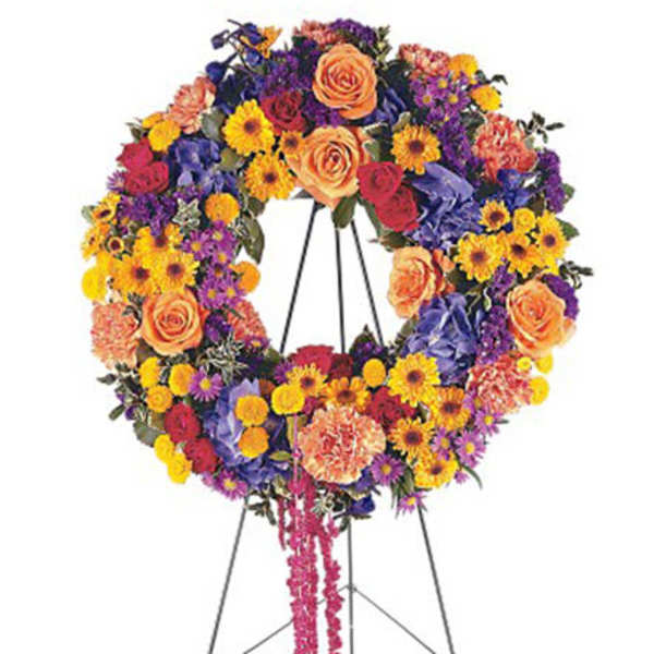 Colorful standing wreath of roses, carnations, and daisies on a metal easel stand