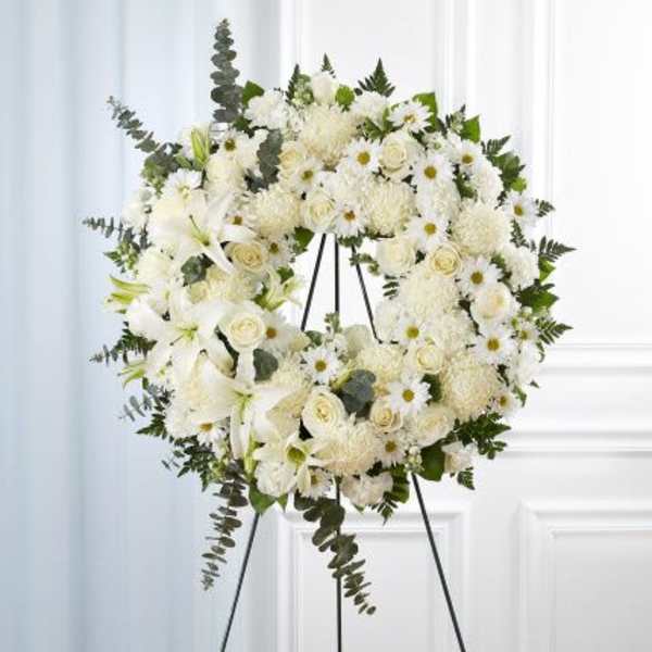 Standing white floral wreath with roses, lilies and mums on a metal easel