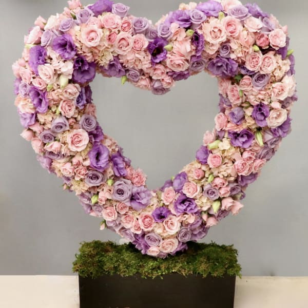 Large open heart of pink and purple flowers on a moss-covered rectangular base