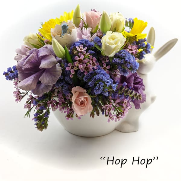 Pastel spring flower arrangement in a white bunny vase with a small bird in an eggshell.