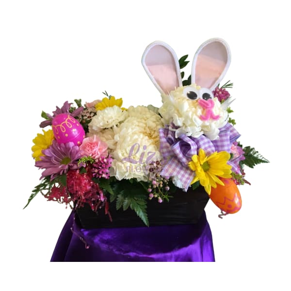 Easter floral basket with bunny face made of white flowers, colorful daisies, and decorative eggs