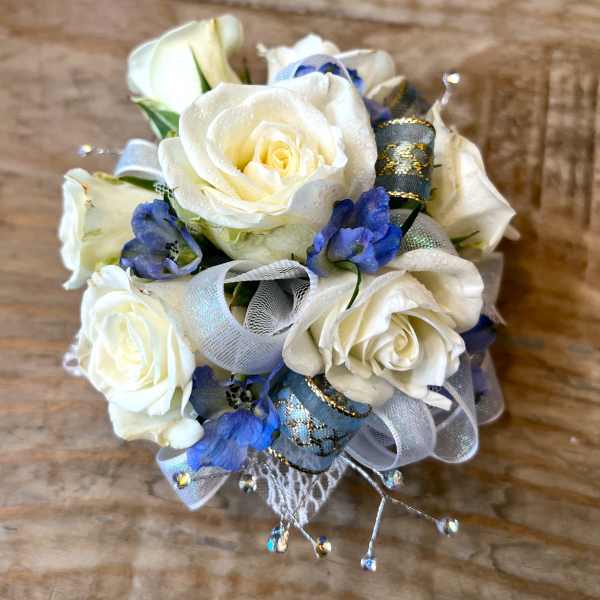 Small corsage of white roses and blue flowers with silver and blue ribbon accents