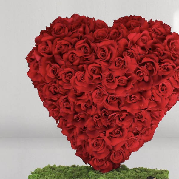 Heart-shaped arrangement of red roses standing on a low moss-covered base