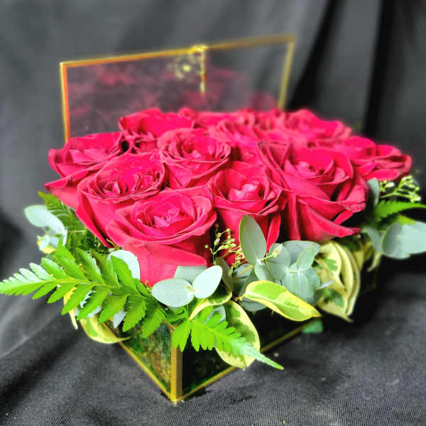 Box arrangement of red roses in a clear square container with the lid propped open